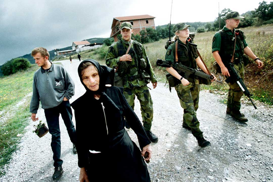 Svenska FN-soldater eskorterar en kvinna till hennes mans grav. Foto:Björn Olsson